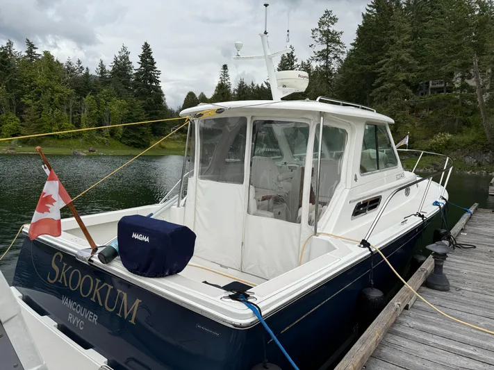 Skookum Yacht Photos Pics 2009 Back Cove 29 boat docked, displaying Canadian flag, surrounded by lush greenery.