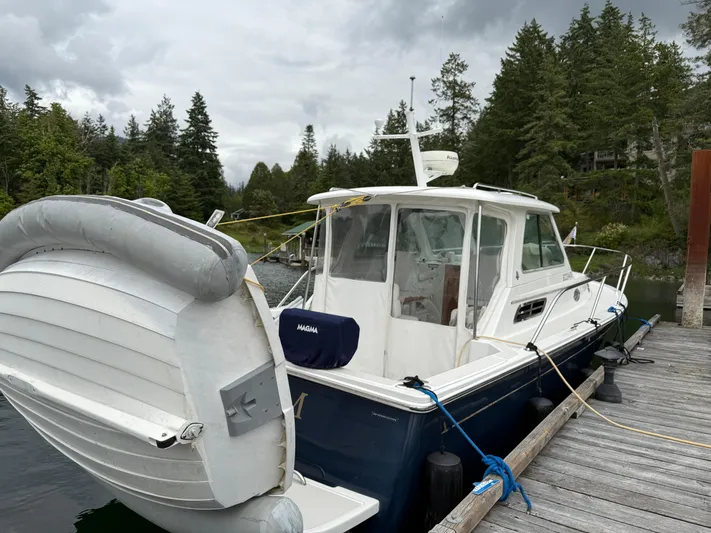 Skookum Yacht Photos Pics 2009 Back Cove 29 boat docked, surrounded by lush trees and cloudy sky.