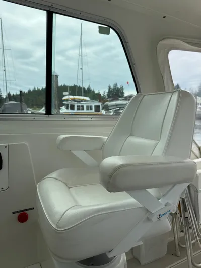 Skookum Yacht Photos Pics Captain's chair inside a 2009 Back Cove 29 boat, with marina view through window.