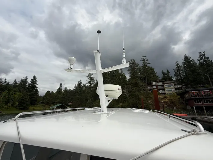 Skookum Yacht Photos Pics 2009 Back Cove 29 boat with radar equipment, docked near forested shoreline under cloudy sky.