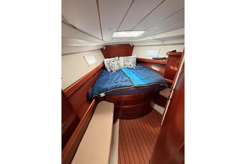 Solmare Yacht Photos Pics Cozy cabin interior of 2005 Beneteau Oceanis Clipper 423 with wooden finish and bedding.