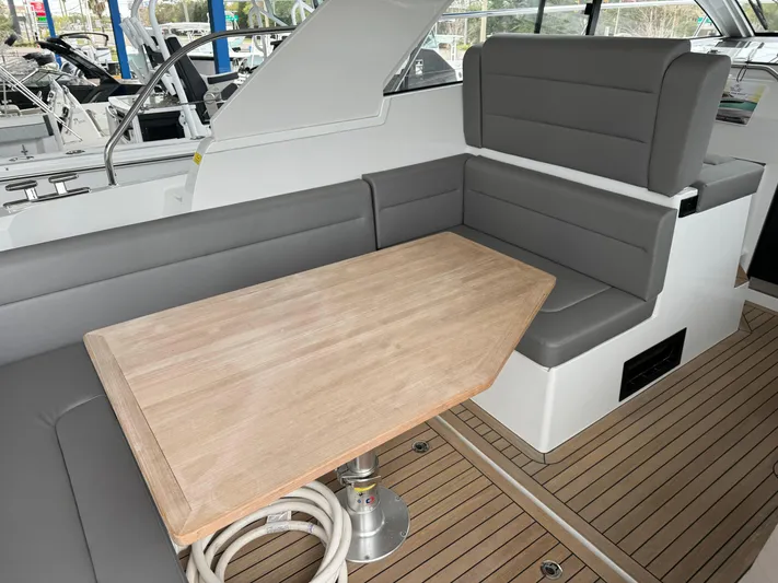 Yacht Photos Pics 2024 Sealine S335V yacht interior with gray seating and wooden table.