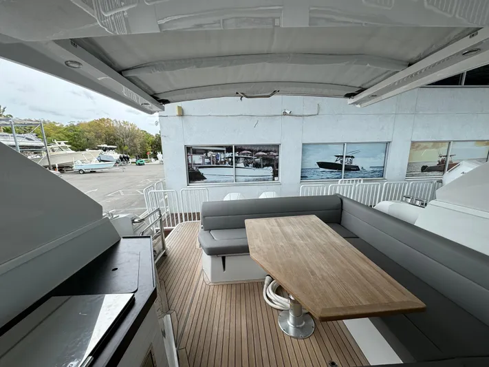  Yacht Photos Pics 2024 Sealine S335V yacht deck with seating and wooden table, docked at marina.