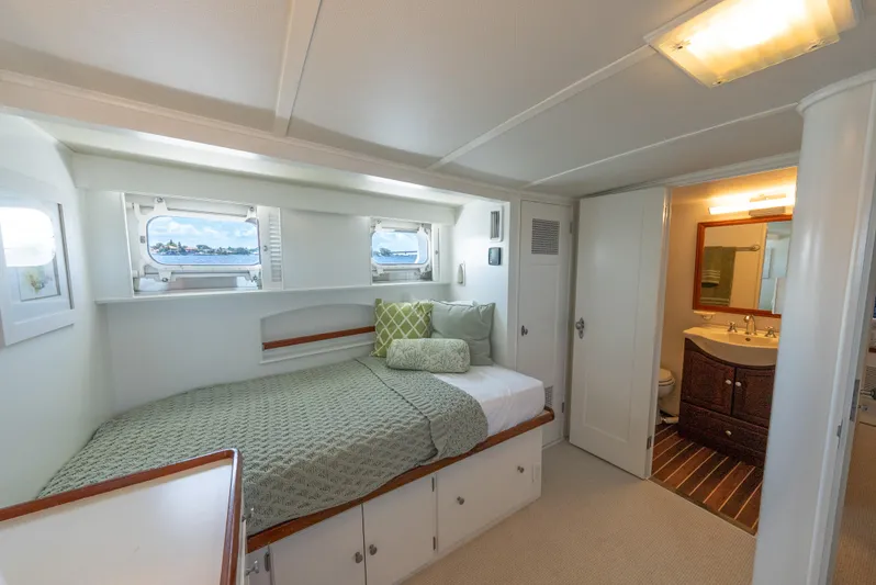 Absolute Yacht Photos Pics 1970 Trumpy houseboat bedroom with cozy bed, porthole windows, and adjacent bathroom.