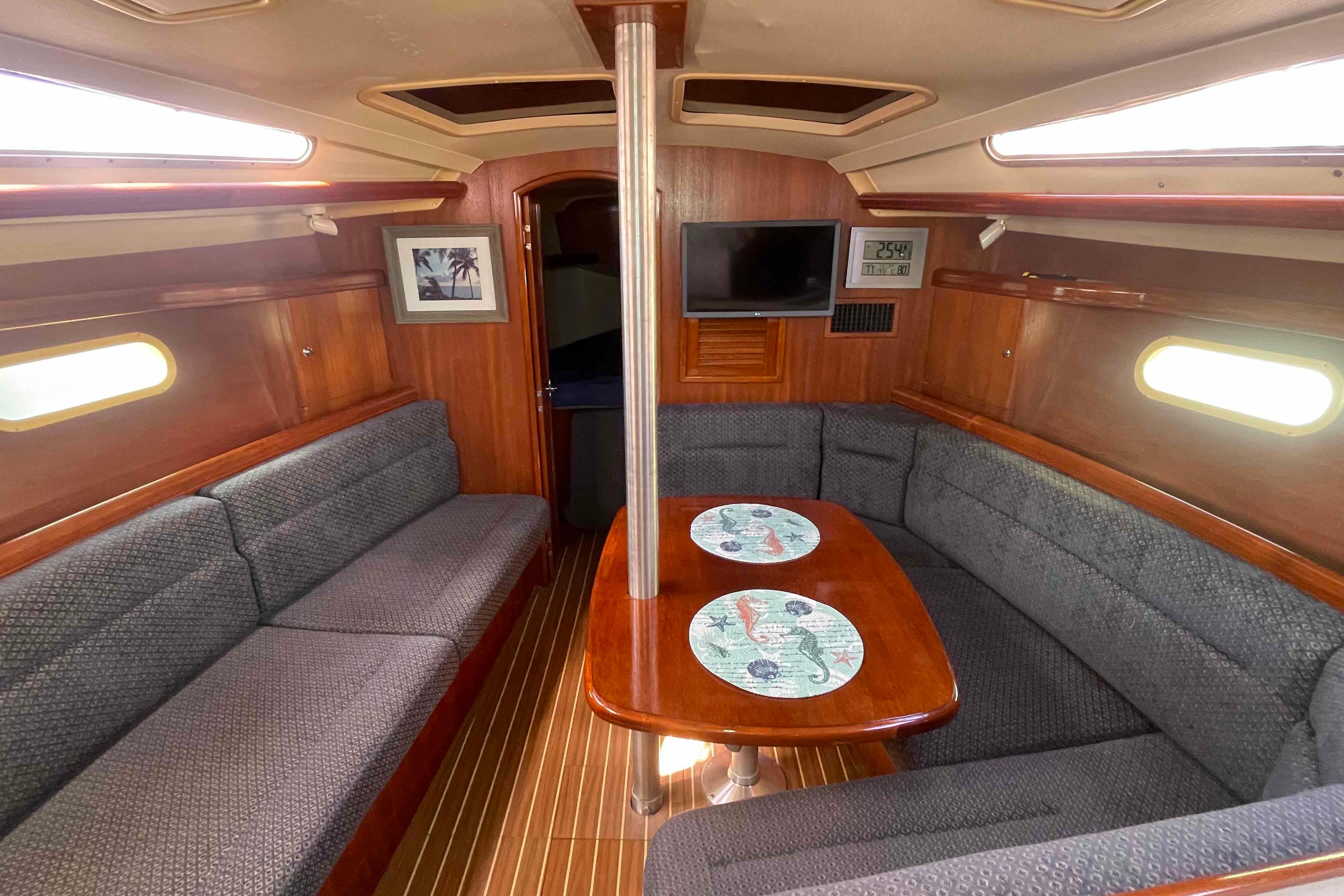 Interior of 2006 Hunter 36 sailboat with cozy seating and wooden table.