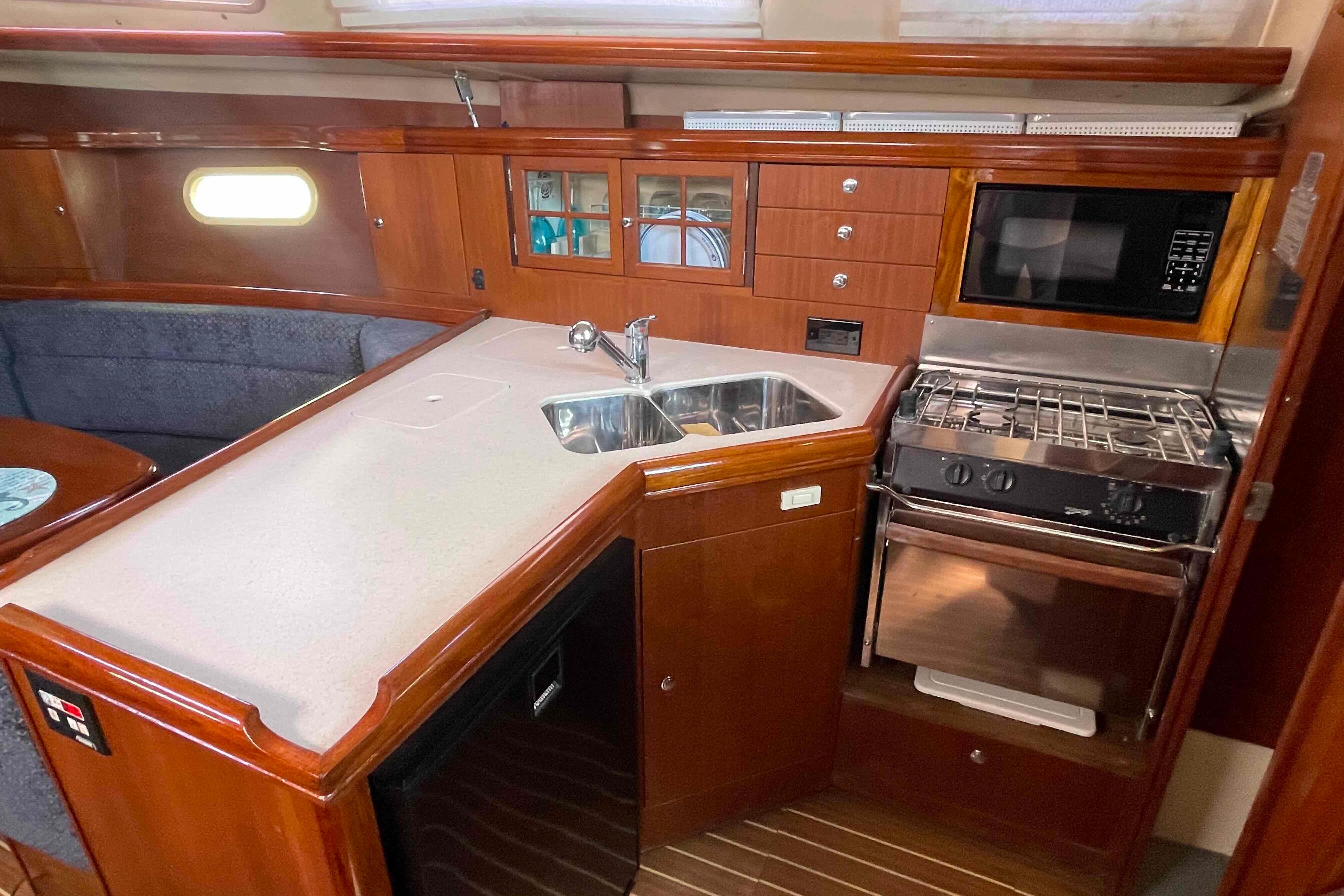 2006 Hunter 36 yacht interior kitchen with wood cabinetry, sink, stove, and microwave.