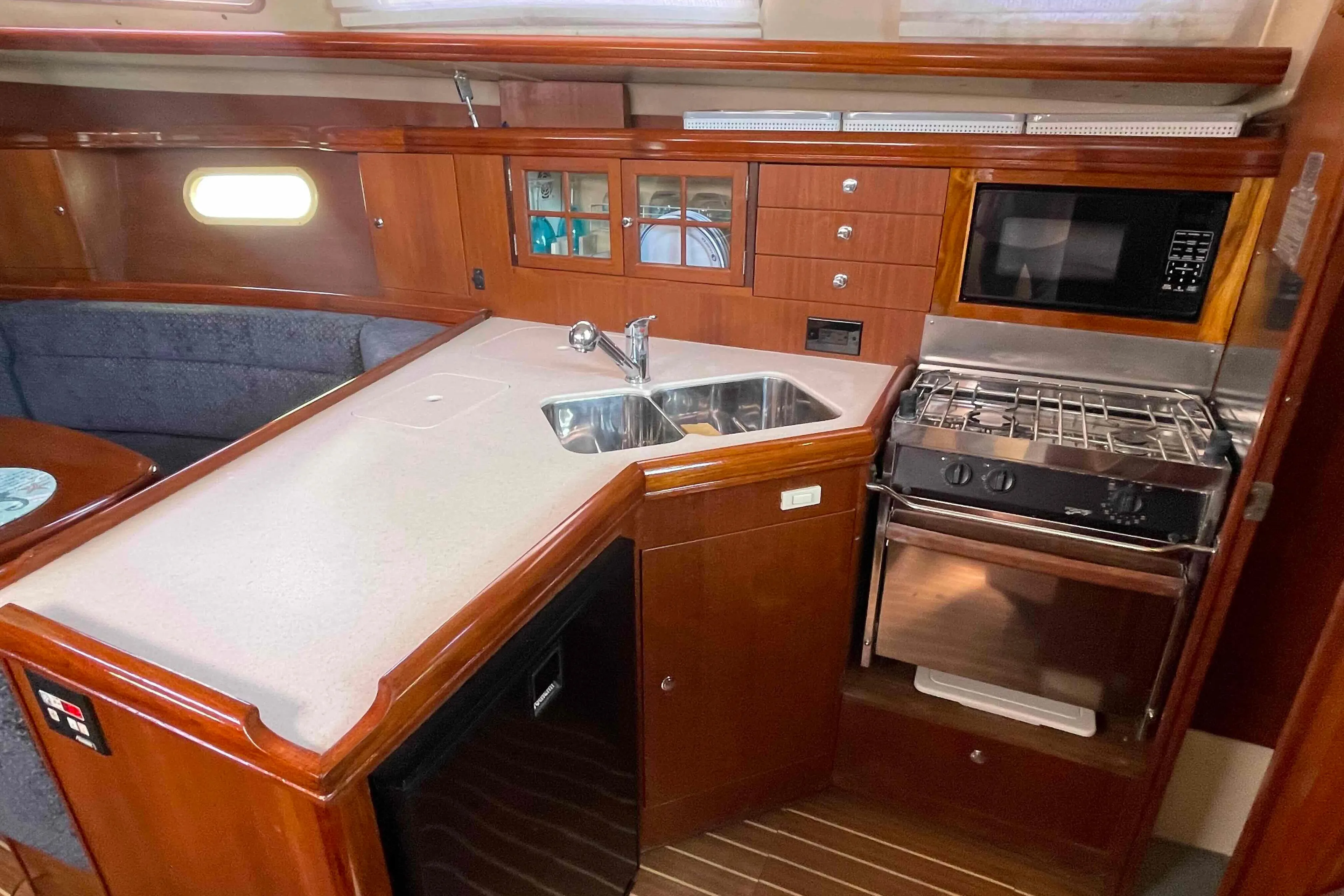 2006 Hunter 36 yacht interior kitchen with wood cabinetry, sink, stove, and microwave.