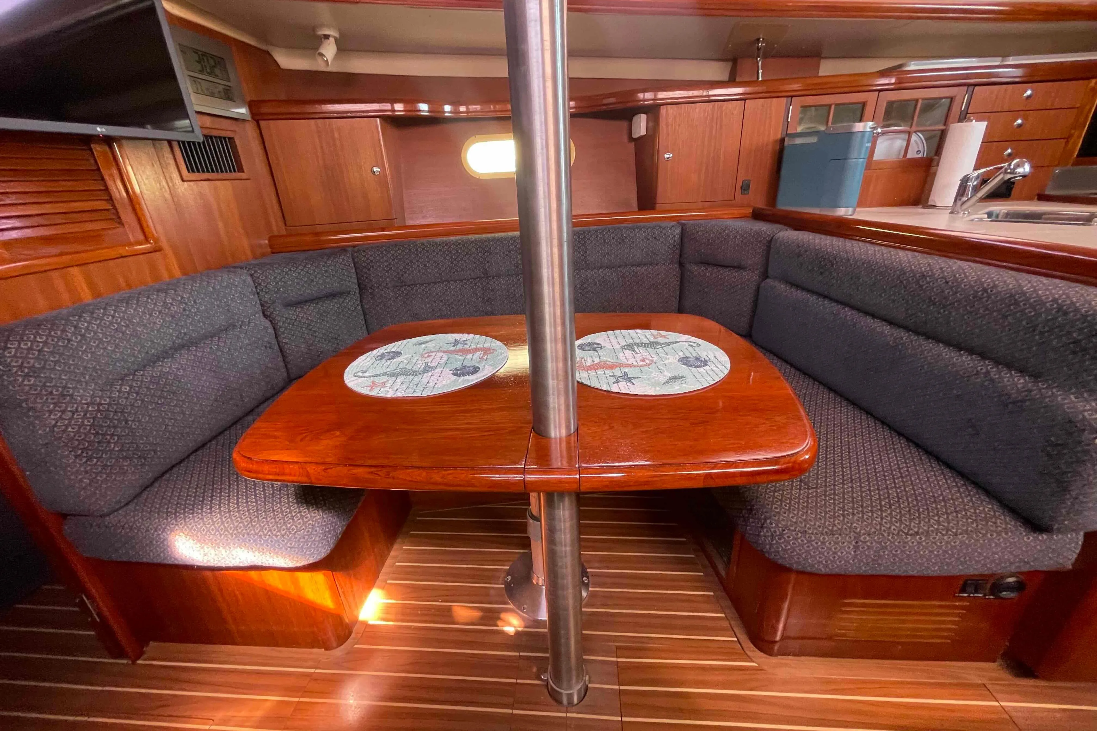Cozy interior of 2006 Hunter 36 sailboat with wooden table and cushioned seating.