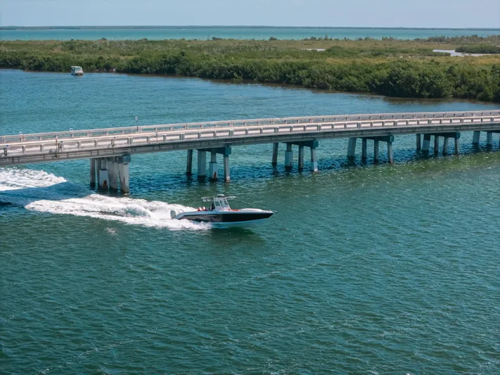  Yacht Photos Pics 2007 Donzi 38 ZF Cuddy boat cruising under a bridge on a sunny day.
