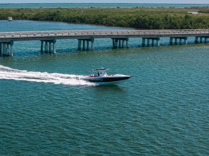  Yacht Photos Pics 2007 Donzi 38 ZF Cuddy boat cruising near a bridge on a sunny day.