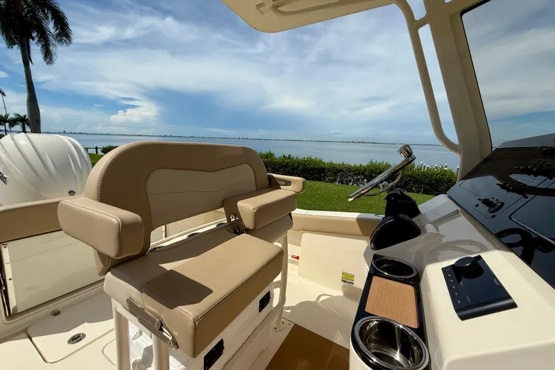  Yacht Photos Pics 2025 Scout 240 XSF boat interior with steering wheel, overlooking serene waterfront.