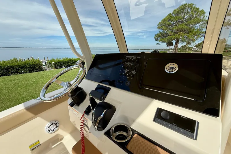  Yacht Photos Pics 2025 Scout 240 XSF boat dashboard with steering wheel and control panel, overlooking scenic waterfront.
