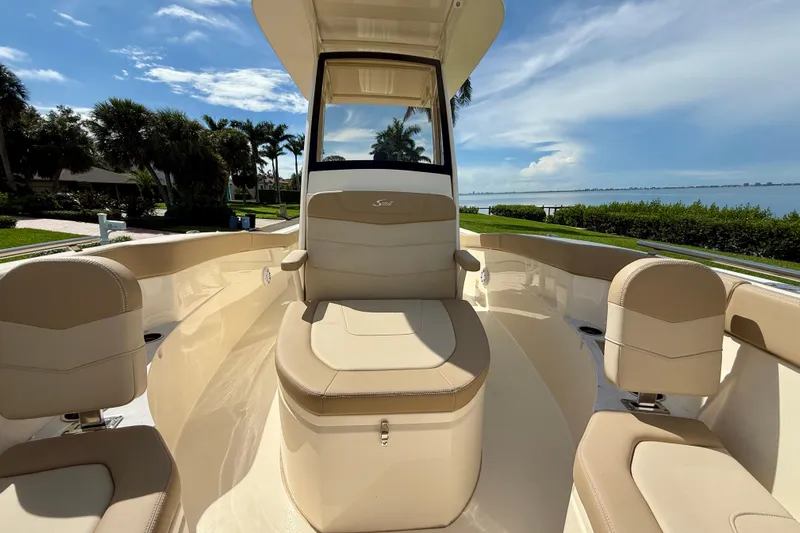  Yacht Photos Pics 2025 Scout 240 XSF boat interior with beige seating, set against a scenic waterfront view.