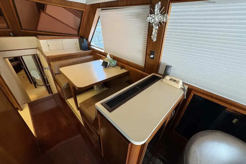 Keepem Flying Yacht Photos Pics Interior of 1985 Hatteras 60 enclosed bridge with dining area and wood accents.
