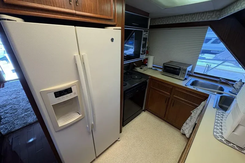Keepem Flying Yacht Photos Pics 1985 Hatteras 60 enclosed bridge kitchen with appliances, wooden cabinets, and large window view.