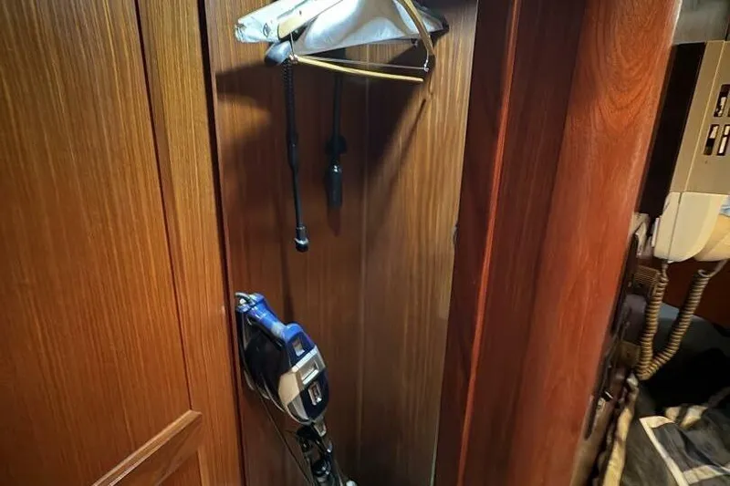 Keepem Flying Yacht Photos Pics Wooden closet interior on 1985 Hatteras 60 enclosed bridge yacht, featuring hangers and equipment.