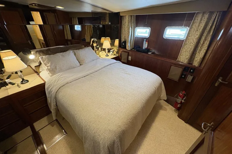 Keepem Flying Yacht Photos Pics Luxurious bedroom interior of 1985 Hatteras 60 enclosed bridge yacht, featuring elegant wood finishes.