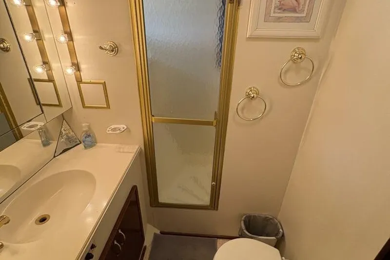 Keepem Flying Yacht Photos Pics Bathroom interior of 1985 Hatteras 60 enclosed bridge yacht, featuring sink, mirror, and shower.
