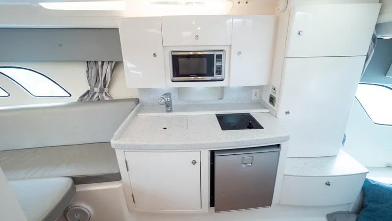  Yacht Photos Pics 2015 Intrepid 400 Cuddy interior with kitchenette, featuring microwave, stove, and compact fridge.