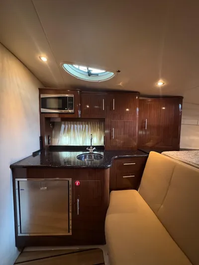 Wine-n-down Yacht Photos Pics 2014 Regal 32 Express yacht interior with kitchenette, featuring wood cabinets and modern appliances.
