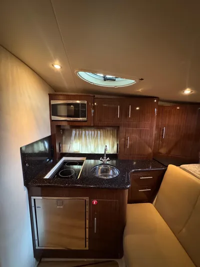 Wine-n-down Yacht Photos Pics 2014 Regal 32 Express yacht interior with kitchenette, featuring microwave, sink, and seating area.