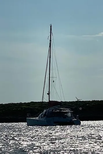 Hazey Daze Yacht Photos Pics Sailboat on shimmering water, Voyage Maxim 2001, silhouetted against the sky.