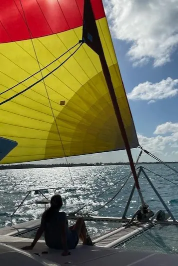 Hazey Daze Yacht Photos Pics Person relaxing on a Voyage Maxim 2001 sailboat with colorful sail on sunny ocean.