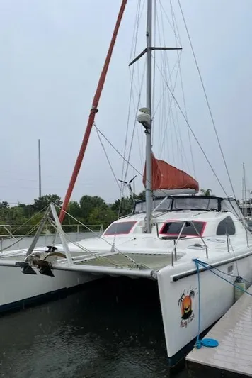 Hazey Daze Yacht Photos Pics 2001 Voyage Maxim catamaran docked, featuring red sail and sleek design.