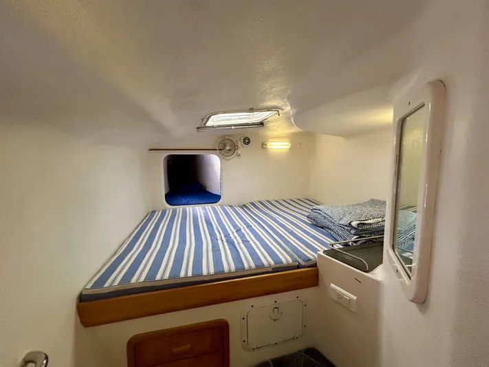 Hazey Daze Yacht Photos Pics Compact cabin interior of 2001 Voyage Maxim with striped bedding and small window.