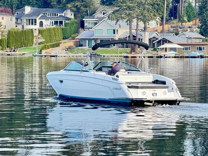  Yacht Photos Pics 2023 Cobalt R8 boat cruising on a serene lake near waterfront homes.
