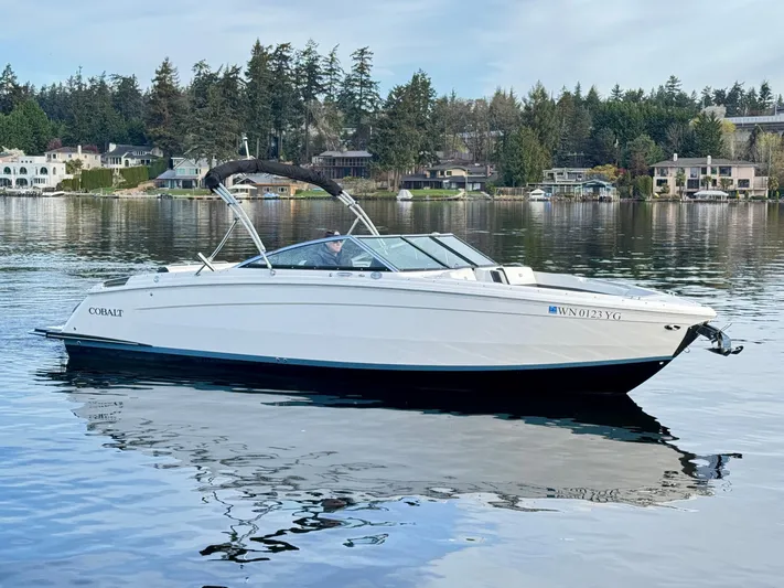  Yacht Photos Pics 2023 Cobalt R8 boat on a serene lake with forested shoreline.