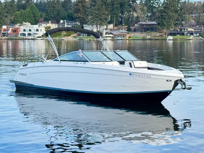  Yacht Photos Pics 2023 Cobalt R8 boat on a serene lake with waterfront homes in the background.