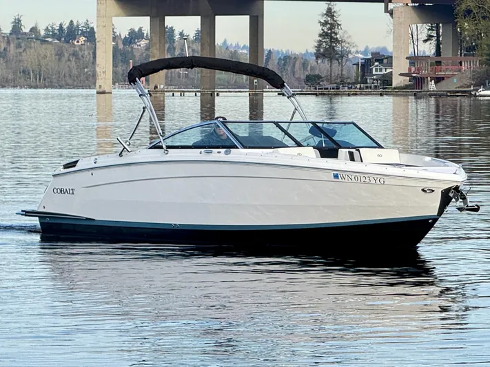  Yacht Photos Pics 2023 Cobalt R8 boat on calm water near a bridge, scenic background.