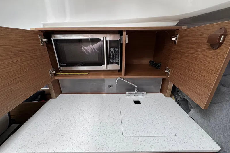  Yacht Photos Pics 2021 Jeanneau Leader 9.0 WA boat kitchenette with microwave, sink, and storage cabinets.