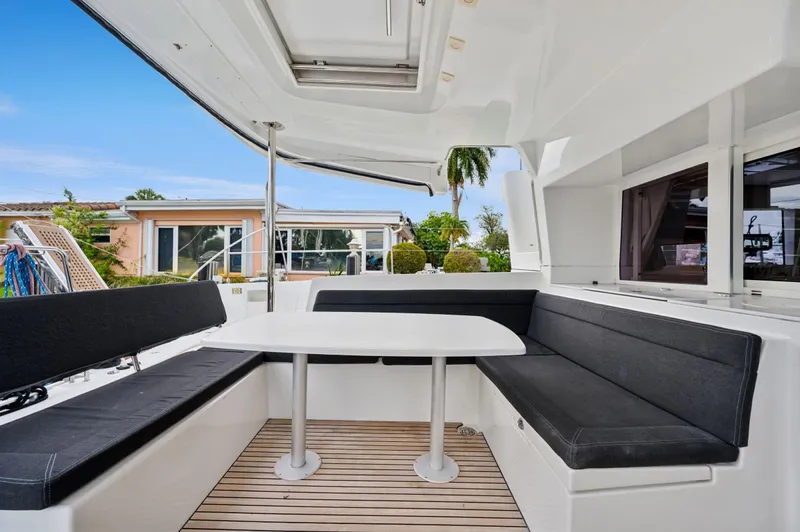 Cruisin Cajun Yacht Photos Pics 2017 Lagoon 450 F yacht with outdoor seating and table, docked near a house.