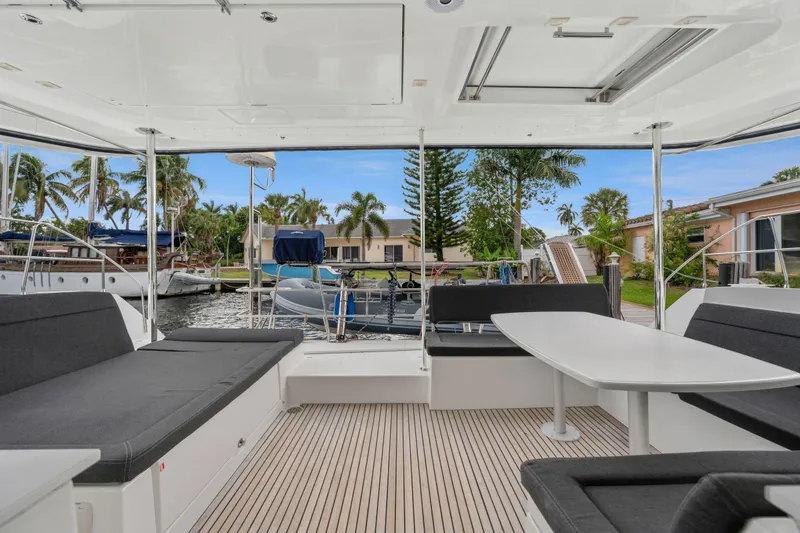 Cruisin Cajun Yacht Photos Pics Spacious deck of 2017 Lagoon 450 F catamaran with seating and table, docked near palm trees.