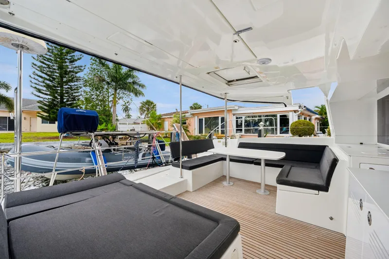 Cruisin Cajun Yacht Photos Pics Spacious deck of 2017 Lagoon 450 F catamaran with seating and table, docked near waterfront homes.