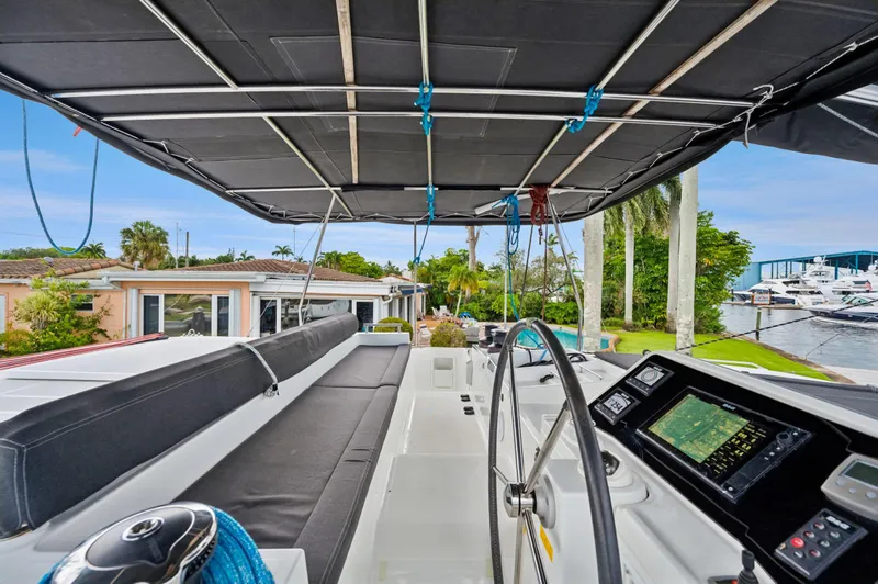 Cruisin Cajun Yacht Photos Pics 2017 Lagoon 450 F catamaran cockpit with navigation equipment and seating, docked near waterfront homes.