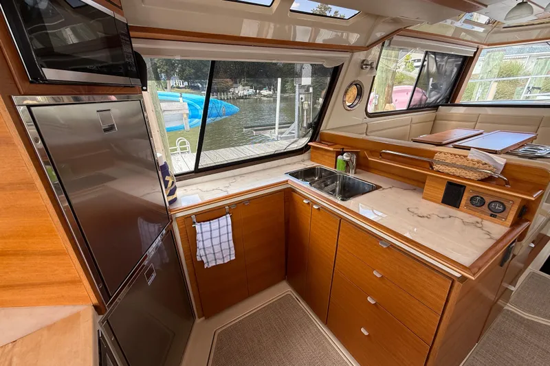  Yacht Photos Pics Luxurious 2021 Ranger Tugs R-41CB yacht kitchen with wood cabinetry and marina view.