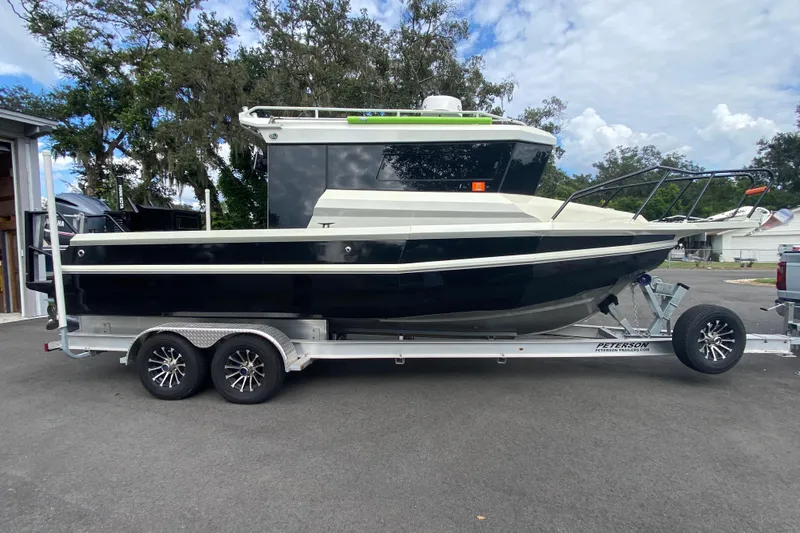 Yacht Photos Pics 2024 Sea King 260 boat on trailer, parked outdoors with trees in the background.