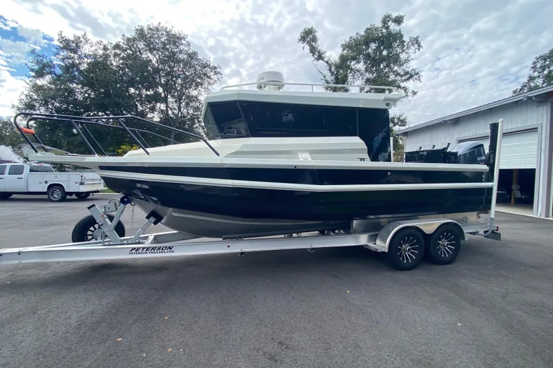  Yacht Photos Pics 2024 Sea King 260 boat on trailer, parked outdoors near trees and a garage.
