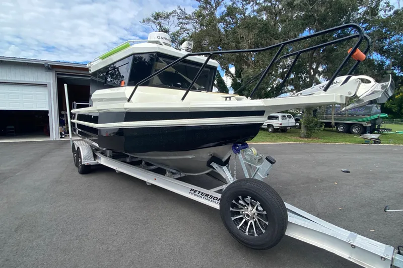  Yacht Photos Pics 2024 Sea King 260 boat on trailer, parked outdoors near a garage.