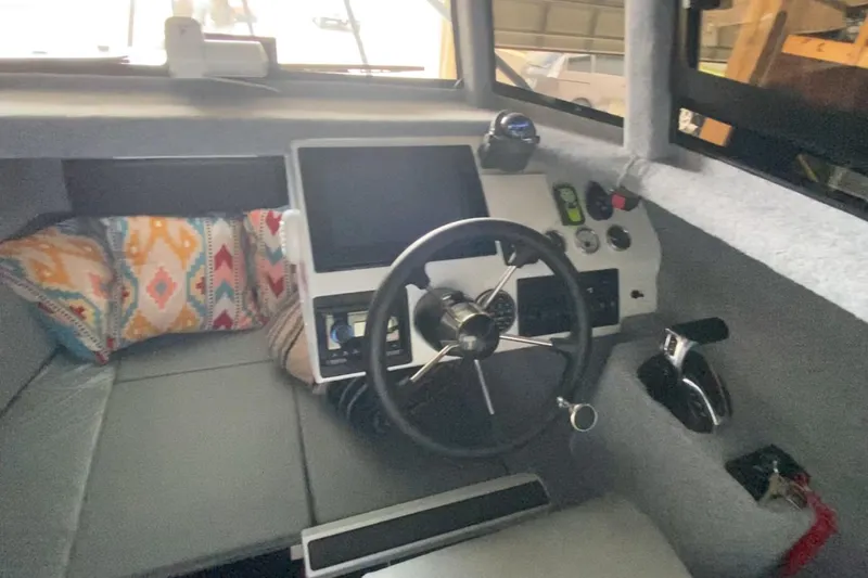  Yacht Photos Pics 2024 Sea King 260 boat interior with steering wheel, control panel, and colorful cushions.