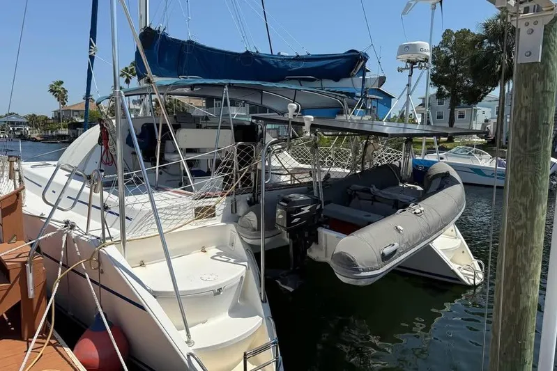  Yacht Photos Pics 1993 Jeanneau Lagoon 37 TPI Catamaran docked, featuring a dinghy and blue sail cover.
