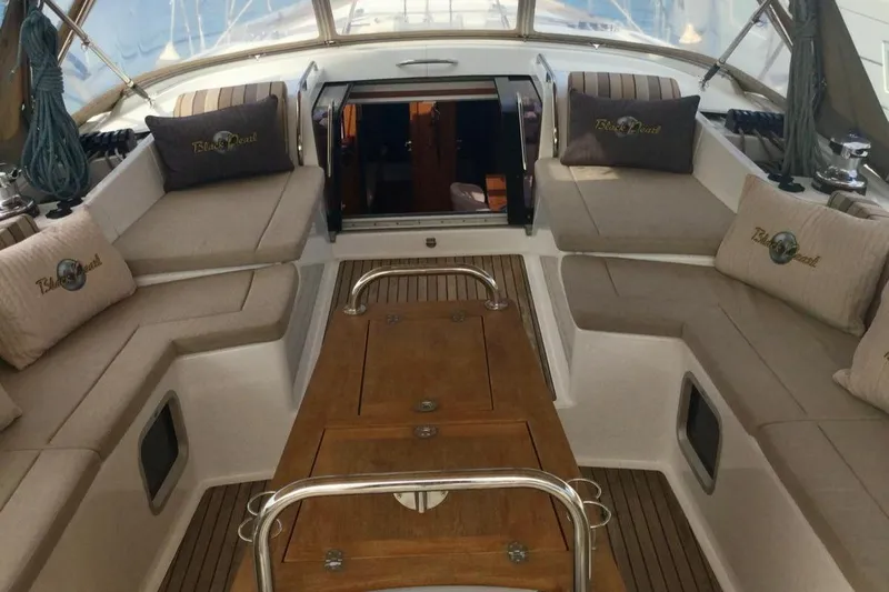 My Black Pearl Yacht Photos Pics Luxurious 2015 Jeanneau 57 yacht cockpit with cushioned seating and wooden table.
