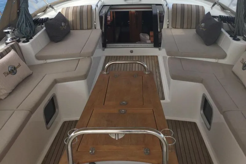 My Black Pearl Yacht Photos Pics Luxurious 2015 Jeanneau 57 yacht interior with cushioned seating and wooden table.