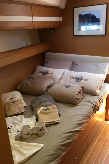 My Black Pearl Yacht Photos Pics Cozy cabin interior of 2015 Jeanneau 57 yacht with bed, pillows, and mugs.