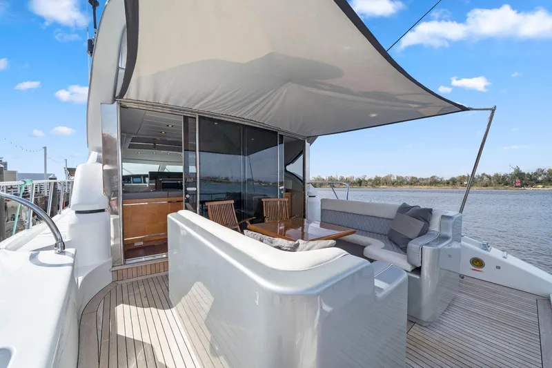 Double Down Yacht Photos Pics 2010 Mangusta 72 Express yacht deck with seating, table, and canopy under blue sky.