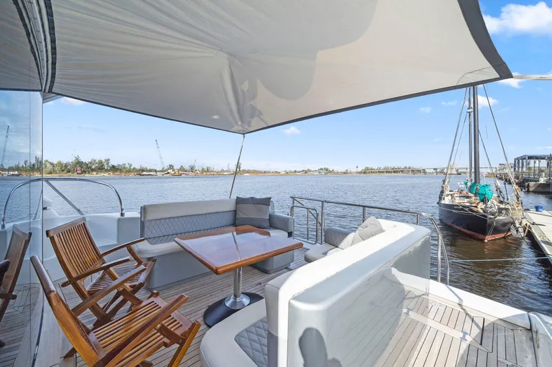 Double Down Yacht Photos Pics Luxurious 2010 Mangusta 72 Express yacht deck with seating and table, overlooking serene waters.