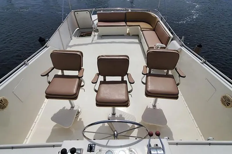 Ruby Yacht Photos Pics 1981 Hatteras 56 Motor Yacht deck with seating and steering wheel, on calm water.